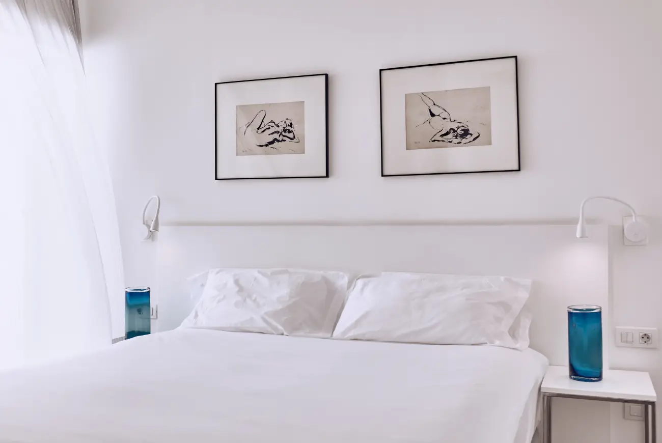 Bright bedroom with a double bed, bedside tables, and framed artwork in the Sapphire One Bedroom Suite at Domes Baobab Suites Tenerife.