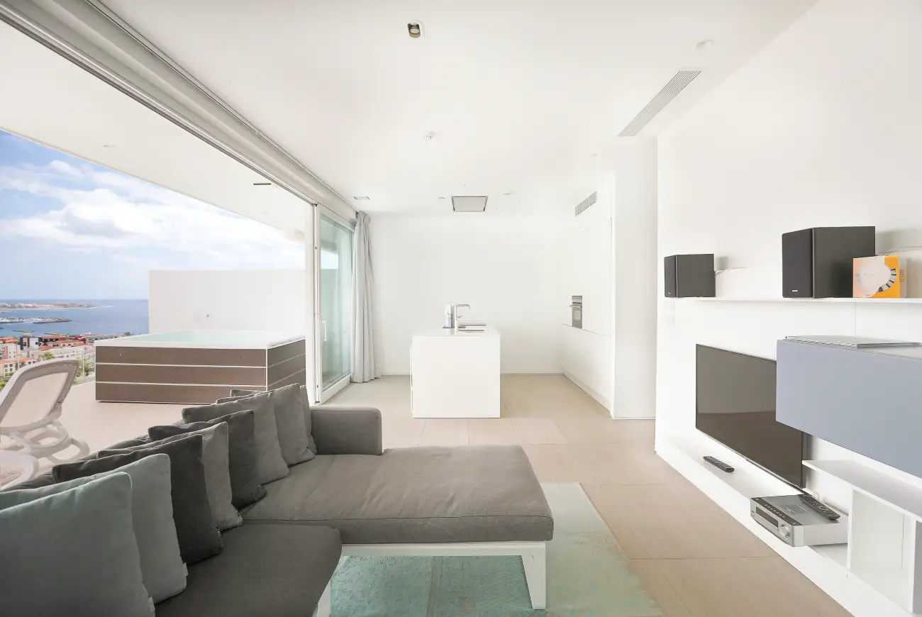 Modern living area with sofa, lounge seating, and large sliding doors leading to a sea-view terrace.
