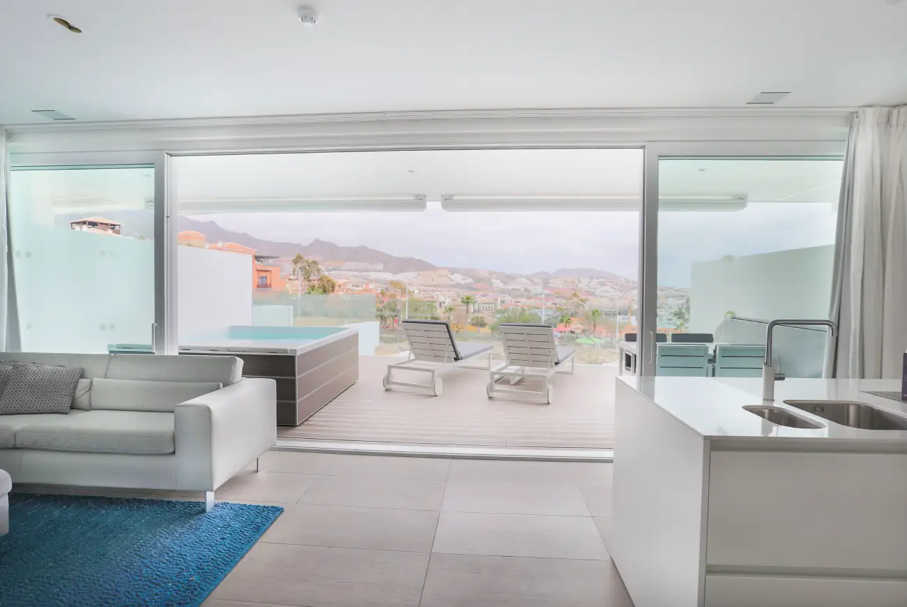Spacious suite interior opening onto a private terrace with panoramic sea views at Domes Baobab Suites Tenerife.