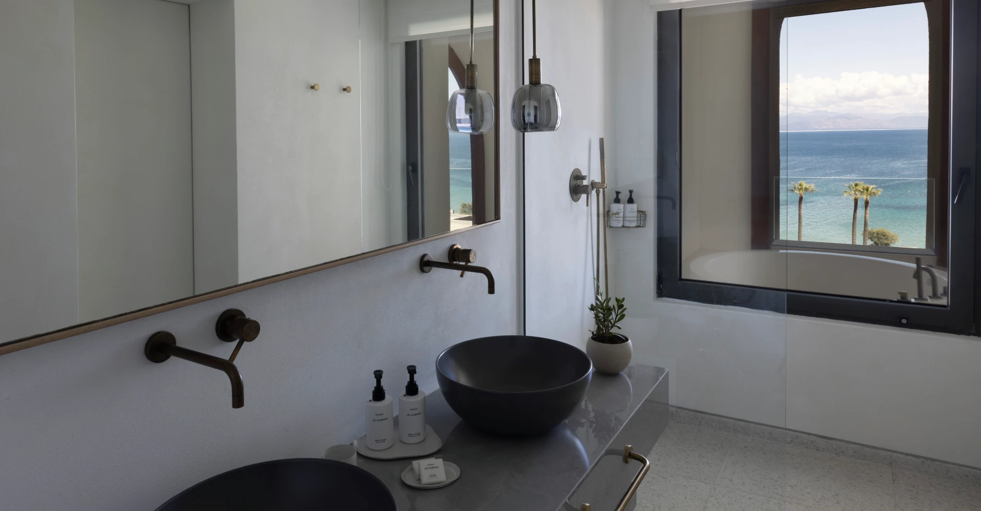 Spacious bathroom of luxury suite with double sink and view of the sea