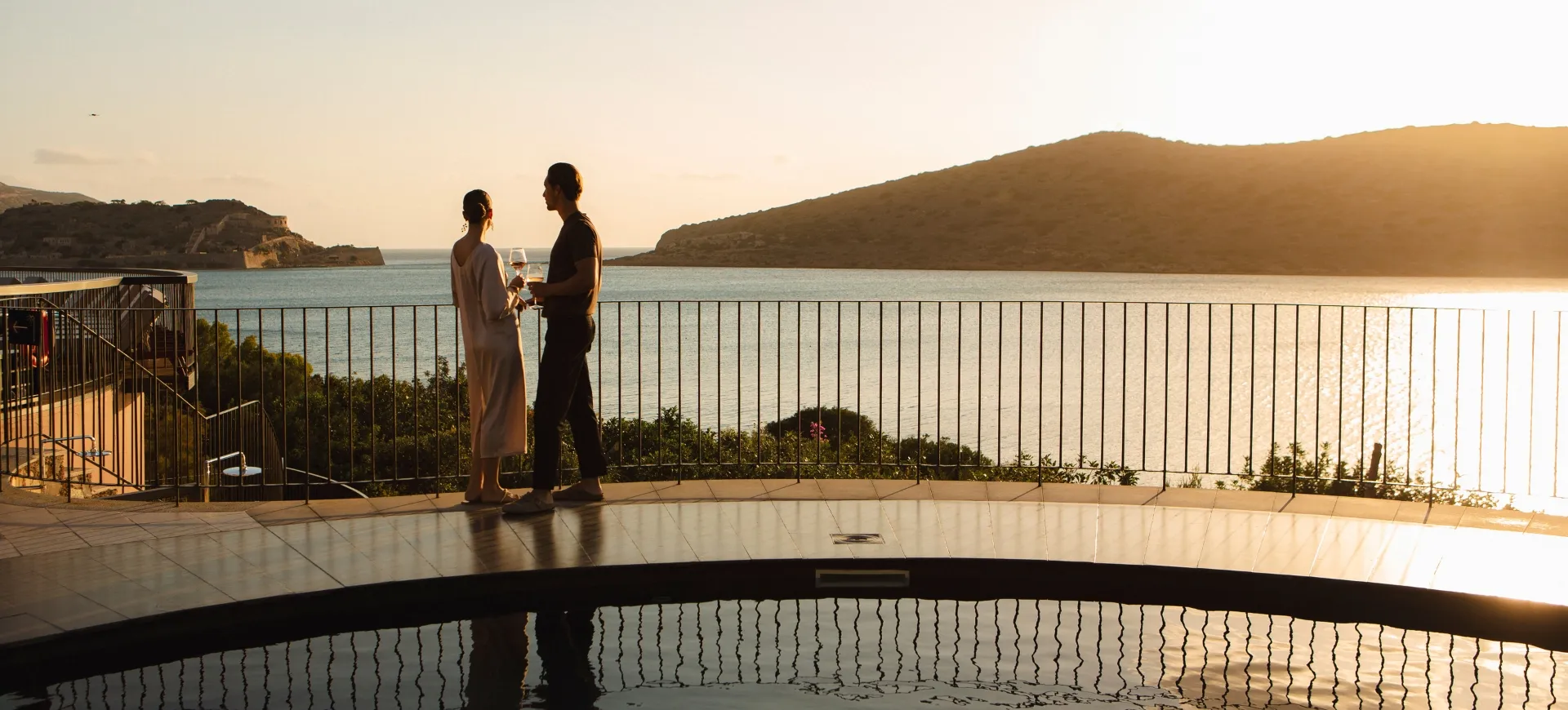 Domes of Elounda Guests Enjoying Spinalonga View while Drinking Wine by the Pool