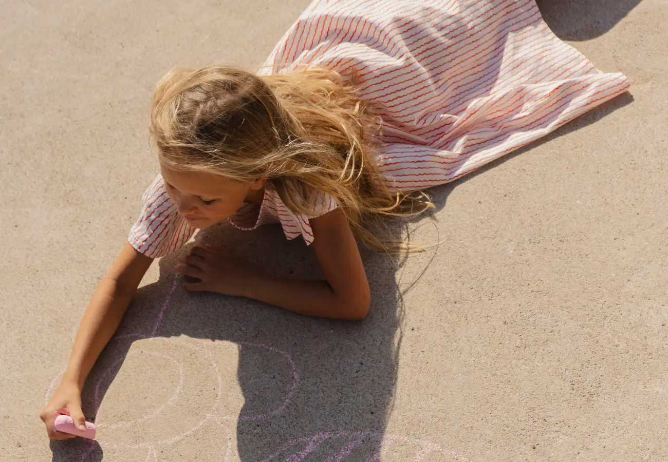 Ein Kind malt im Sand am Strand von Domes of Elounda