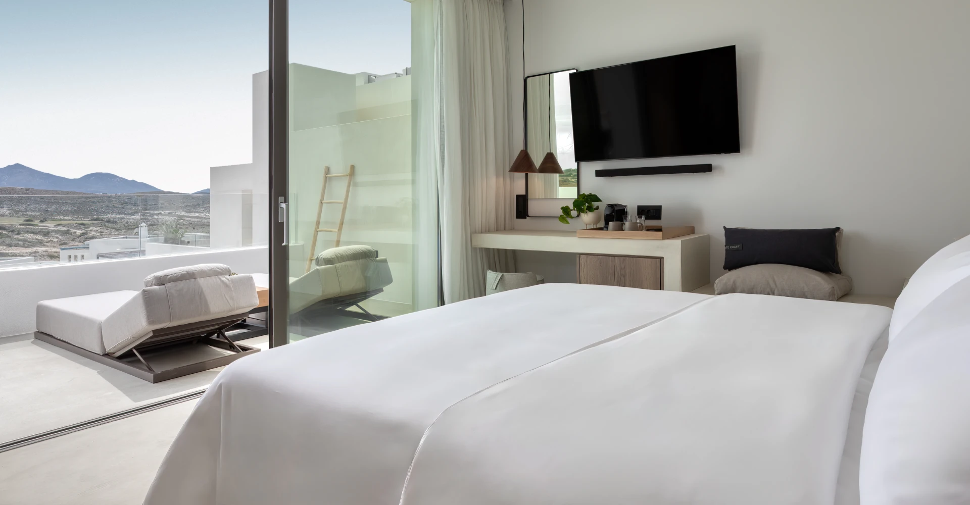 Luxury deluxe suite with king bed and balcony with horizon view at Domes White Coast Milos