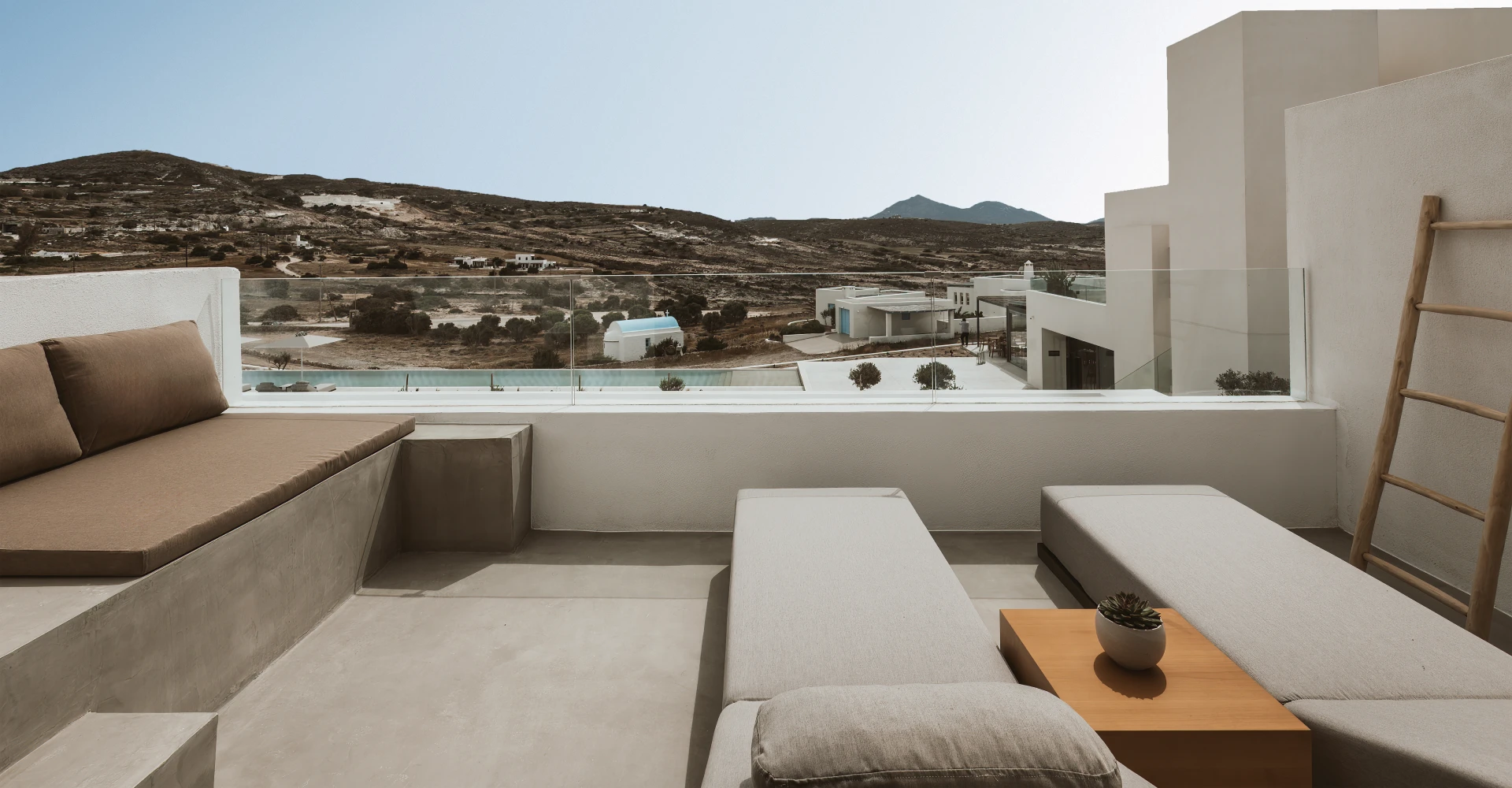 Spacious balcony with sun loungers and pool view at Domes White Coast Milos