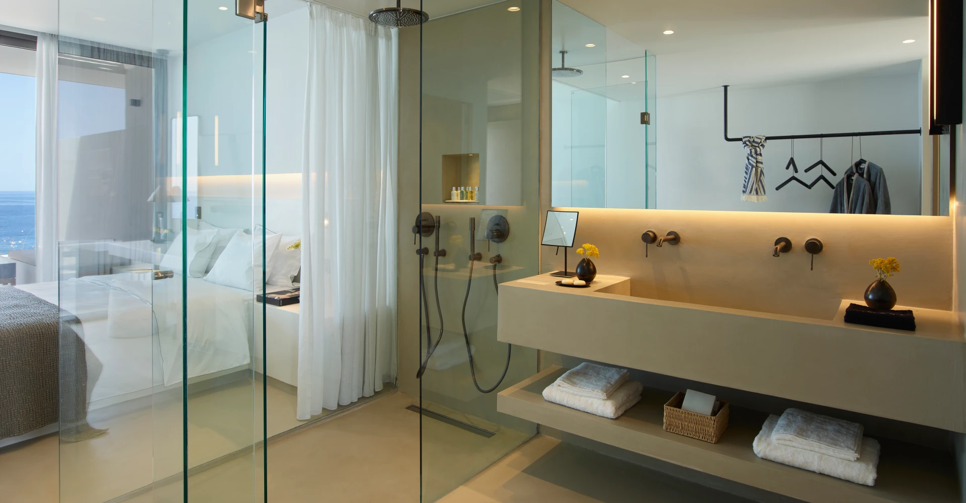 Bright deluxe suite with concrete double vanity bathroom and glass door at Domes White Coast Milos