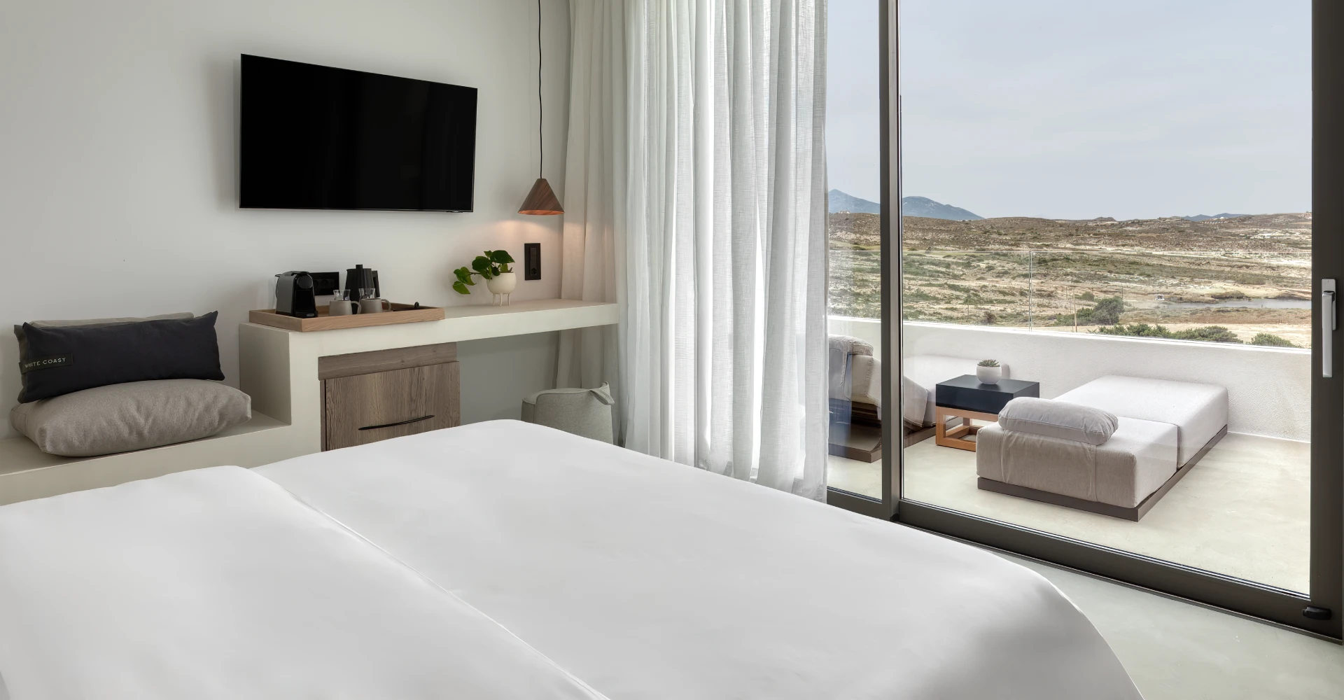 Luxury suite with comfortable king size bed, spacious working space and veranda with sunloungers at Domes White Coast Milos