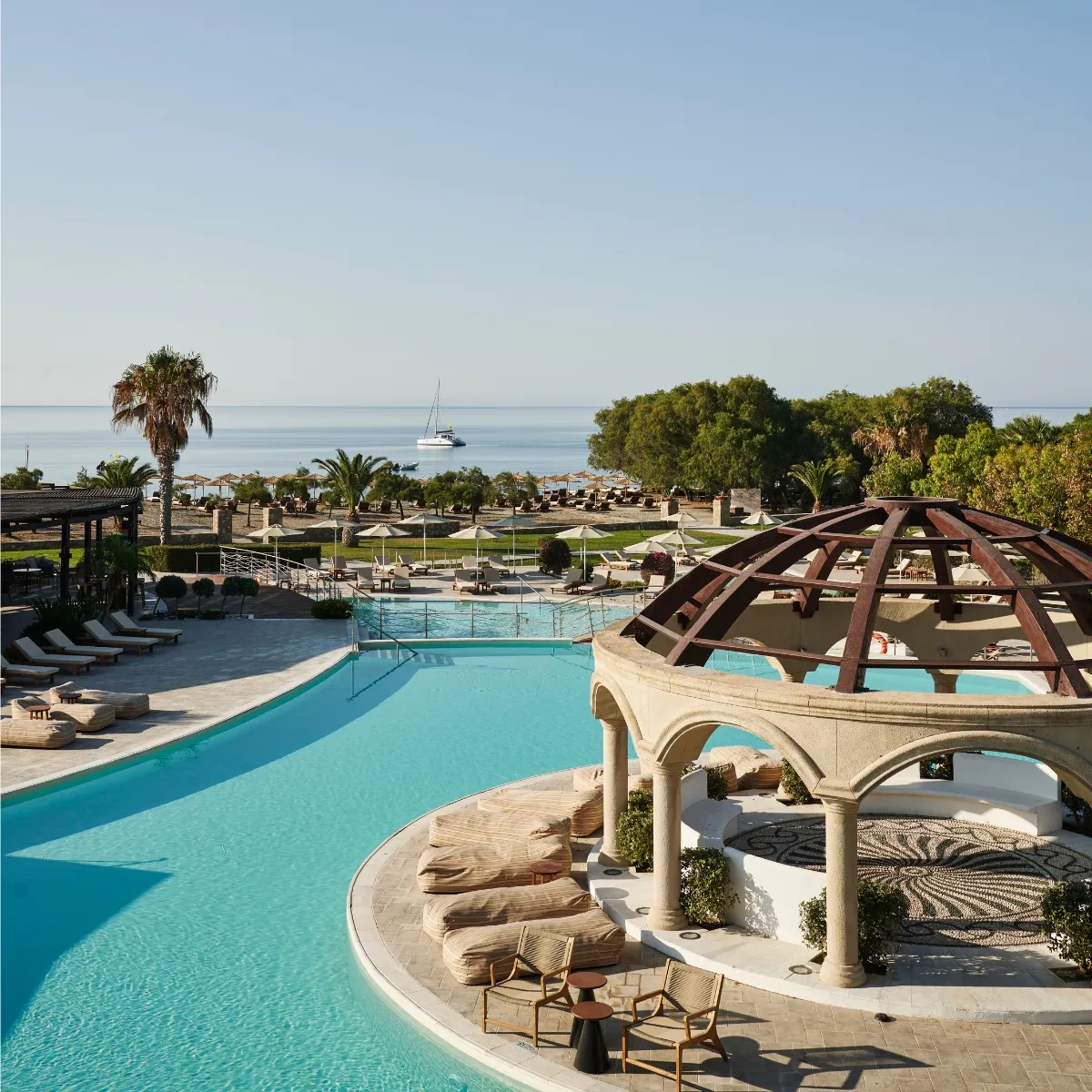 Aulūs Lindos Rhodes resort pools with sea view and lush surroundings.